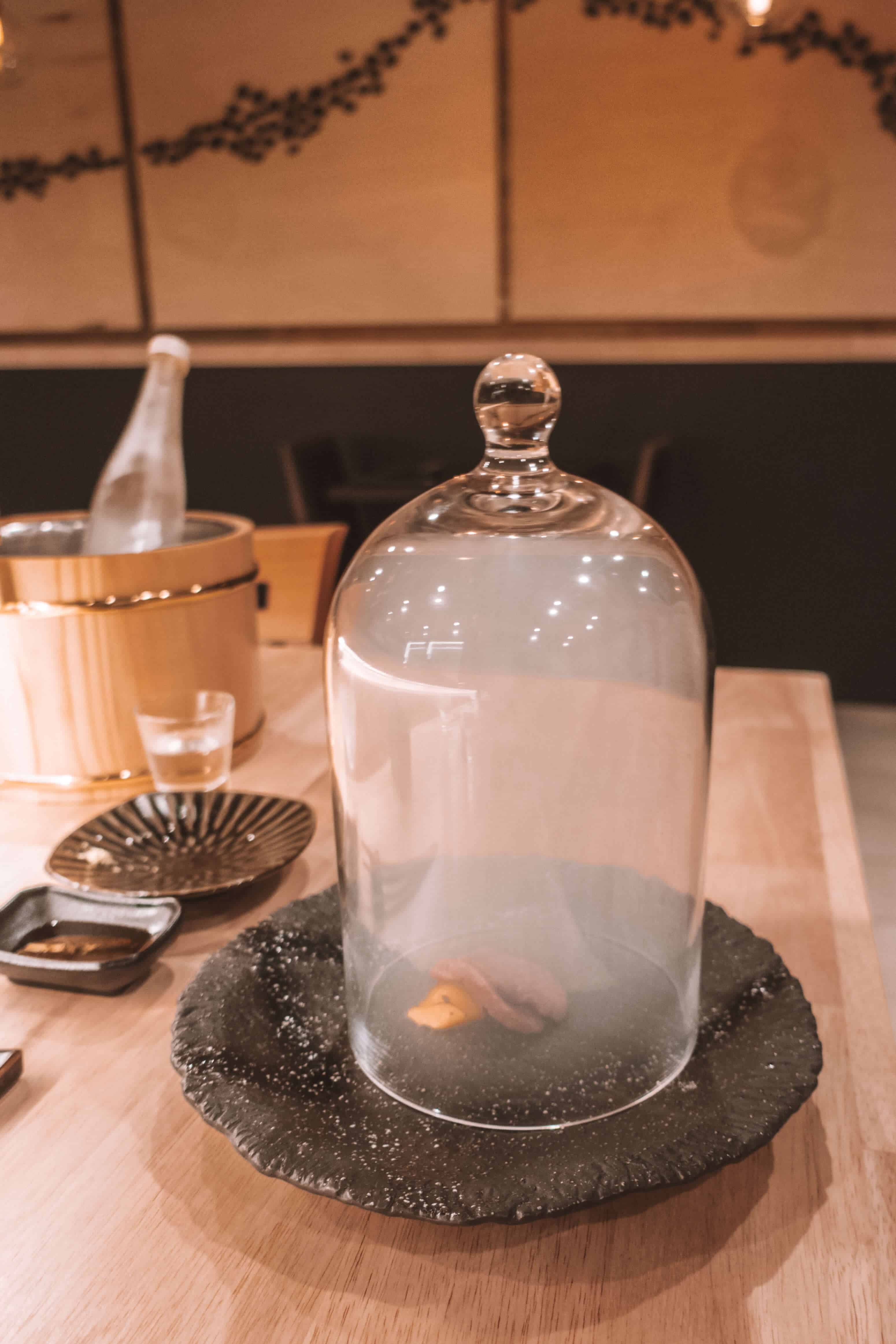 Final beef dish presented in a glass smoking cloche dome at Rebel Omakase in Laguna Beach