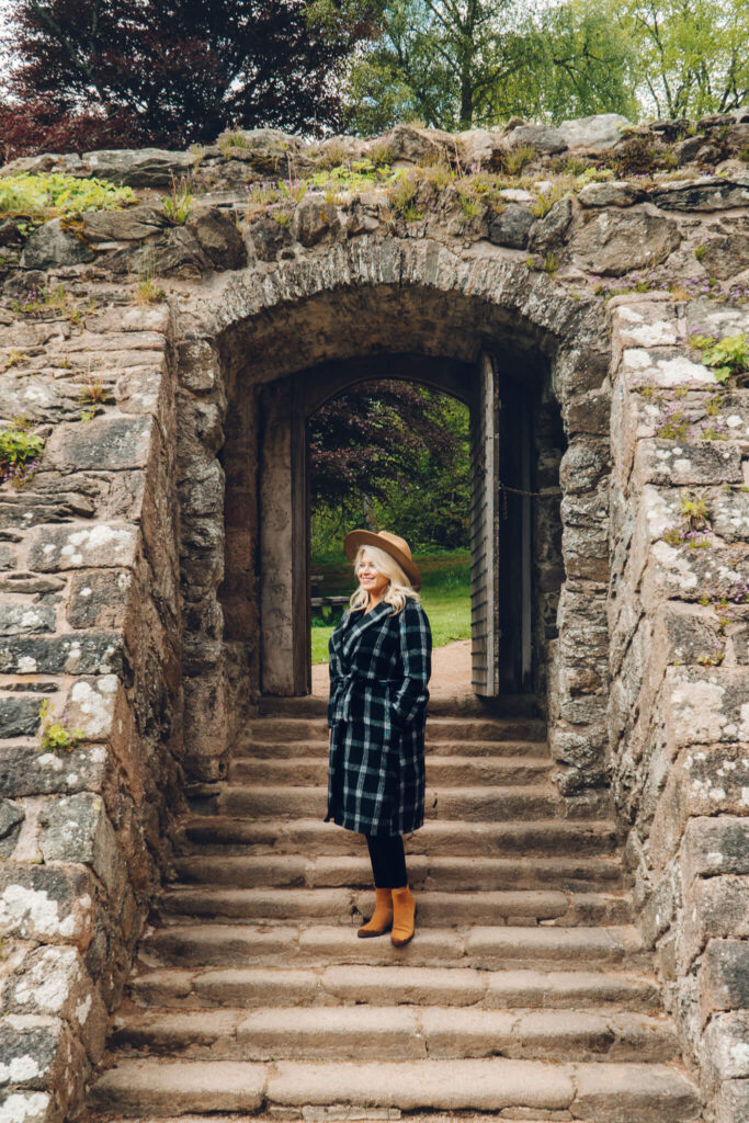 Laura wearing a plaid jacket and suede tan boots in Scotland